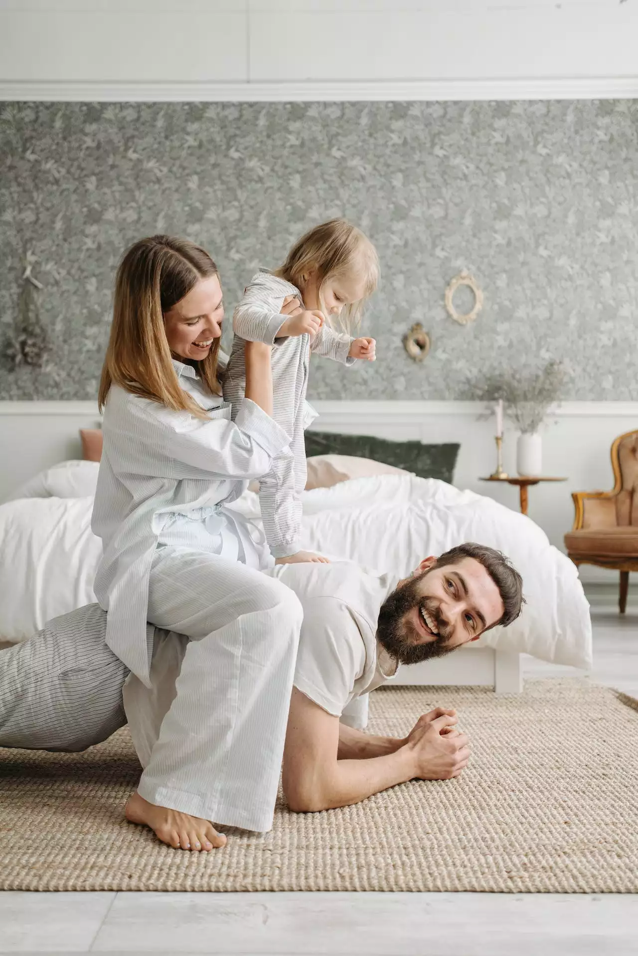 Two parents playing with a toddler in a bedroom